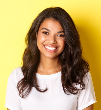 Close-up of attractive african-american woman, smiling and looking happy, standing over yellow background.